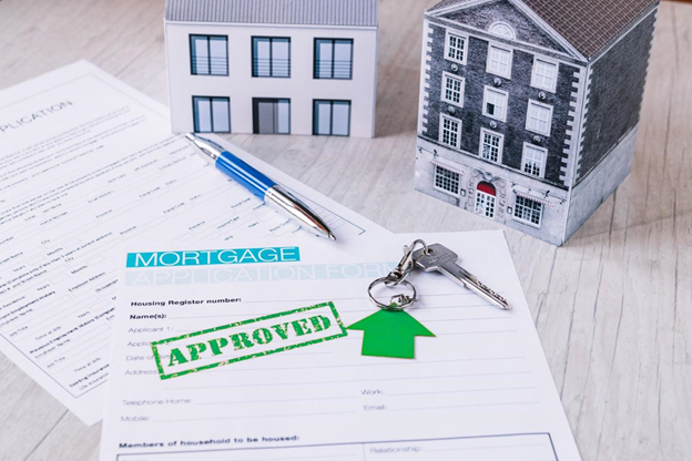Miniature house with approved mortgage application and house keys on table